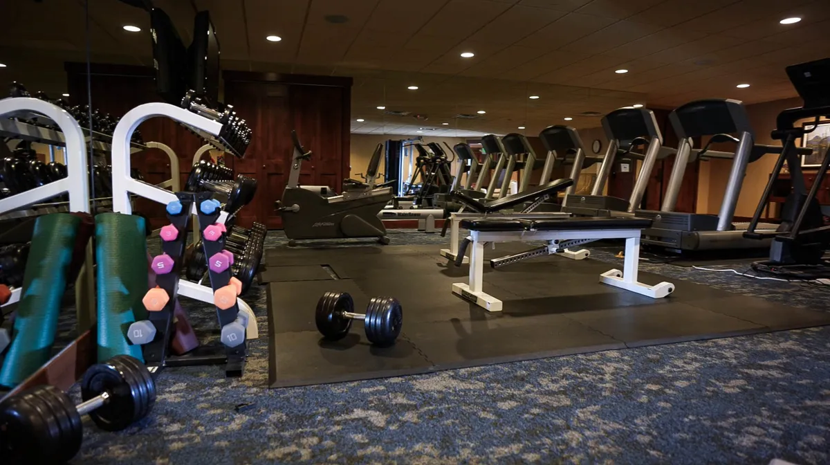 This image depicts a well-equipped fitness facility with treadmills, dumbbells, and a weight bench. The environment is clean and motivational, ideal for guests looking to maintain their routines while traveling.