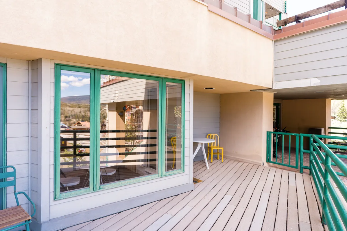 A bright, open balcony featuring colorful chairs and large windows, basking in sunlight. The space is cheerful, suggesting a perfect spot for morning coffee or stargazing at night, with a partial view of the surrounding outdoor environment.